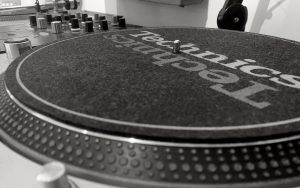 This image shows a close up of a Technic 1200 turntable and a Pioneer DJ mixer