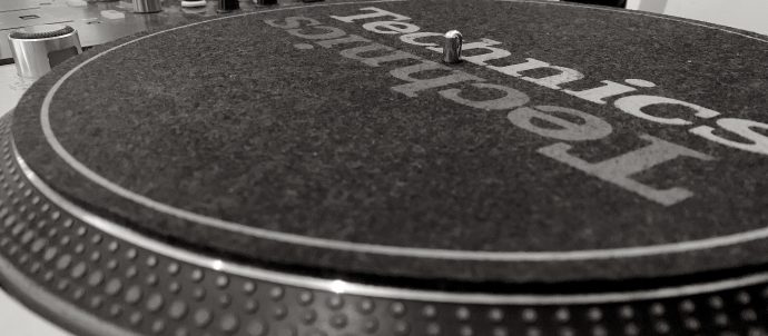 This image shows a close up of a Technic 1200 turntable and a Pioneer DJ mixer