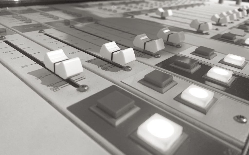 This image shows a close up of the fader and control buttons of the broadcast board at Vancouver Co-op Radio CFRO 100.5 FM