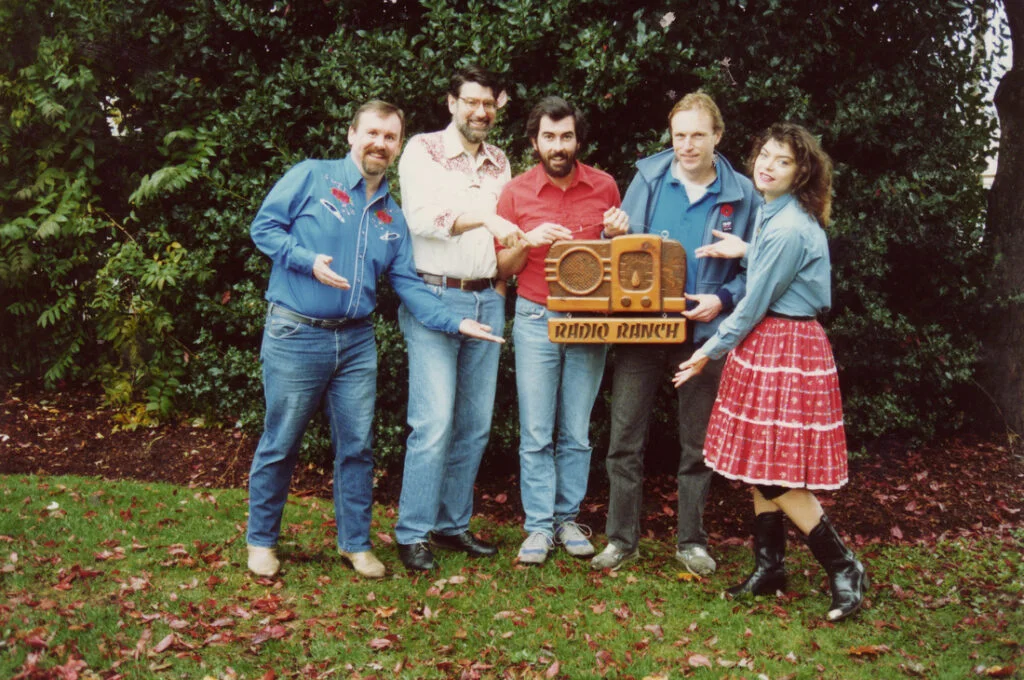 Radio Ranch crew posing with wood carved show logo