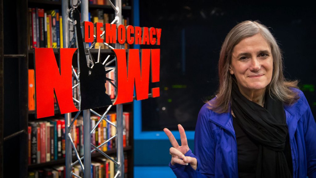 democracy now reporter next to sign